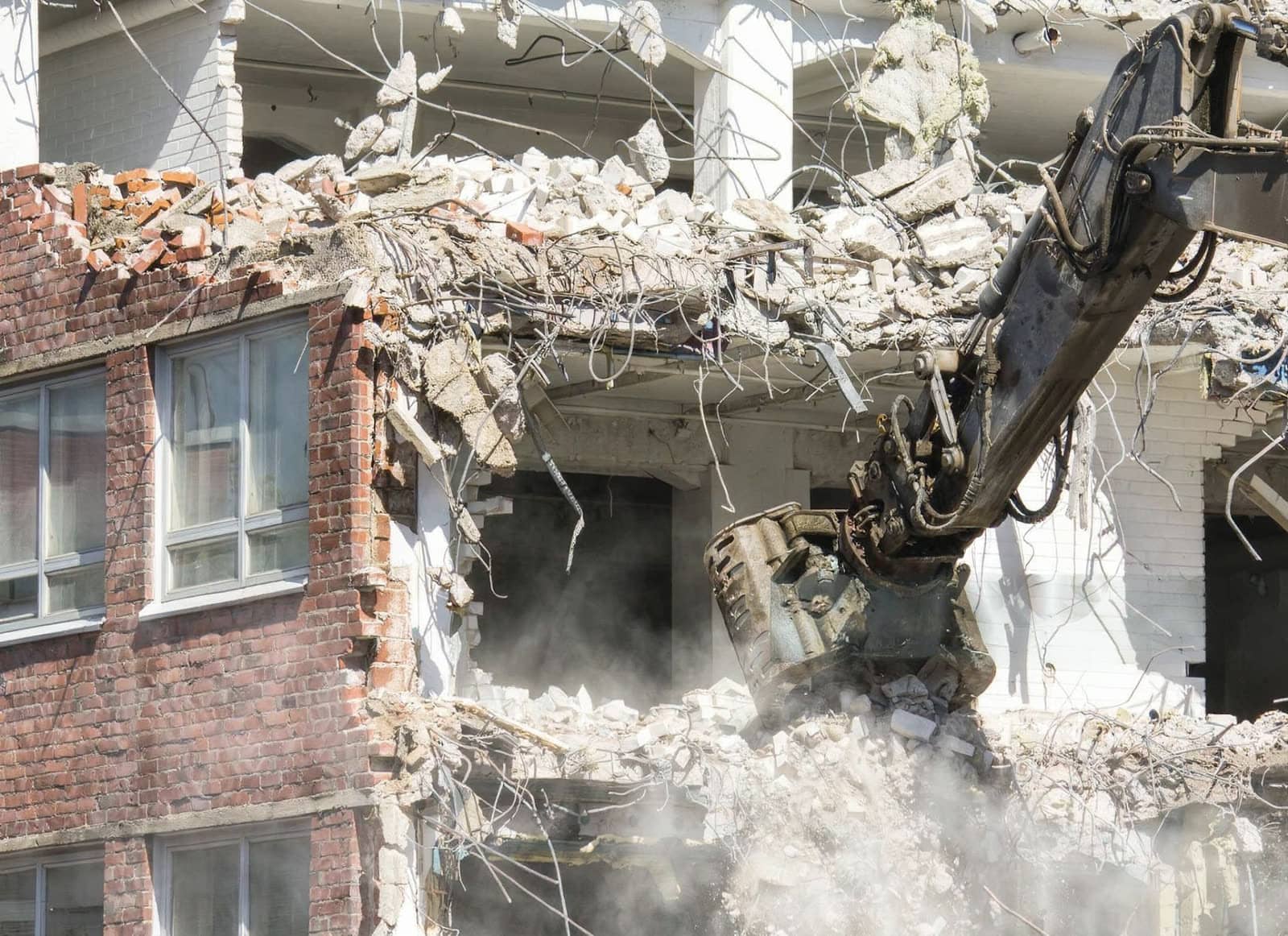 Excavator tearing down a brick building
