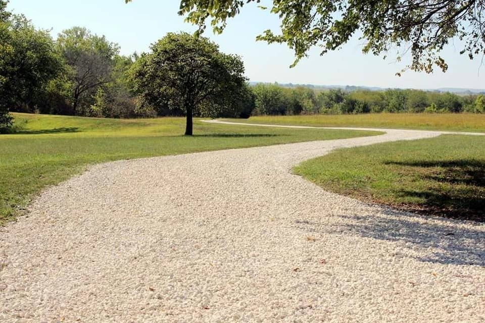 Curving gravel driveway through a mowed Kansas pasture