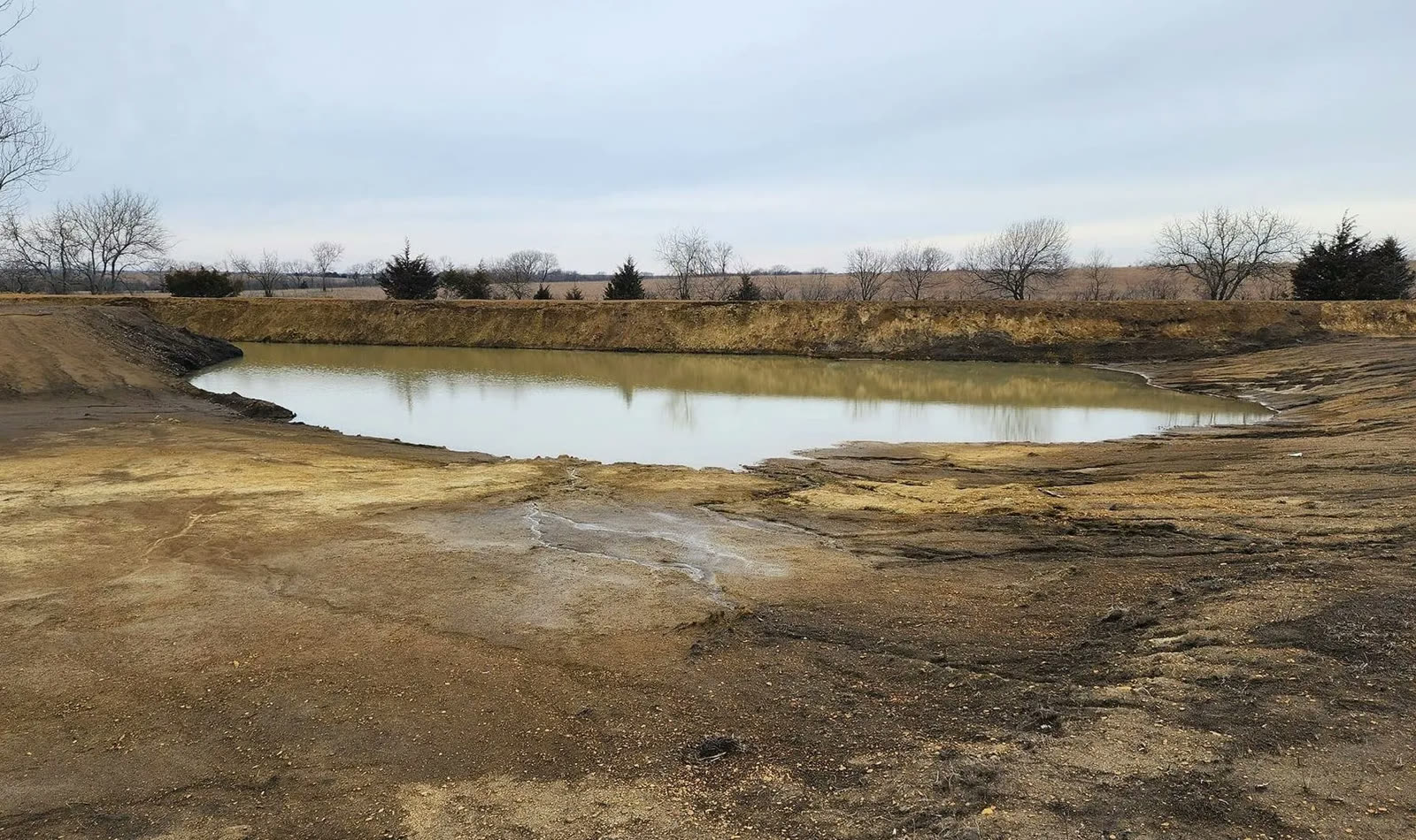 Newly dug pond filling with water in a Kansas field